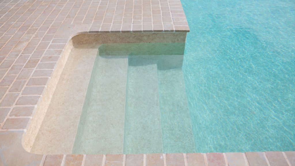 Sfeerbeeld van een buitenzwembad met ingebouwde trap, afgewerkt met folie Alkorplan Touch textuur "Sublime"